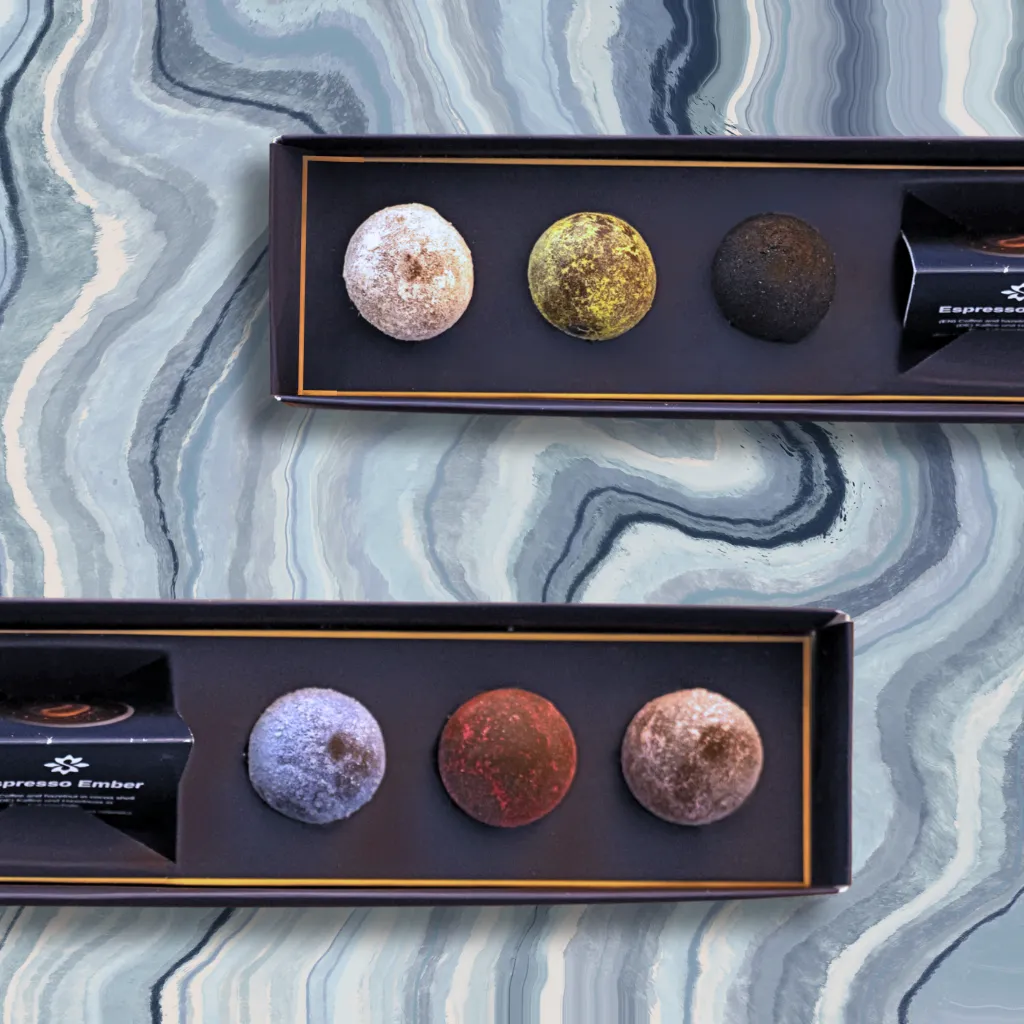 Two open boxes with Senarro Bliss Balls on a marble background